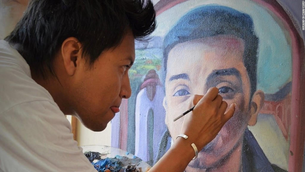 A member of the 43 Artist Group is pictured working on the portrait of one of the 43 students killed on their way to a protest (CNN.)